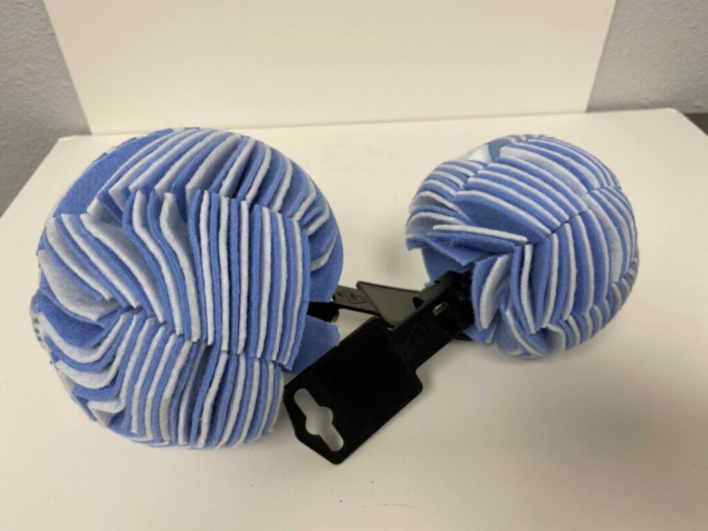 Pair of blue and white striped hand mittens connected by a black strap.