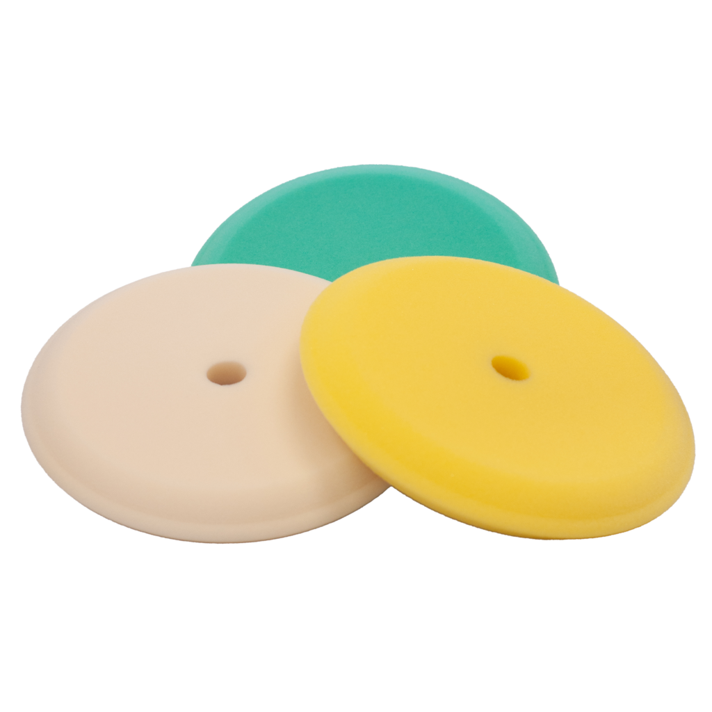 Three colorful foam polishing pads with central holes.